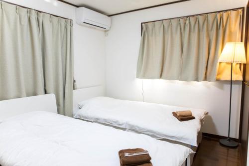 two beds in a room with a window at Tokyo Aoto House in Tokyo