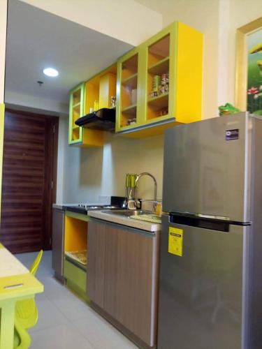 a kitchen with a stainless steel refrigerator and yellow cabinets at Nica's Place Property Management Services at Horizons 101 Condominium in Cebu City