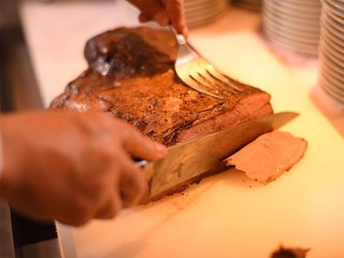 a person cutting a piece of meat with a knife and fork at Urabandai Lake Resort Goshiki no Mori in Kitashiobara