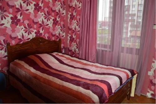 um quarto com uma cama com papel de parede floral cor-de-rosa em Akaki's Apartment em Batumi
