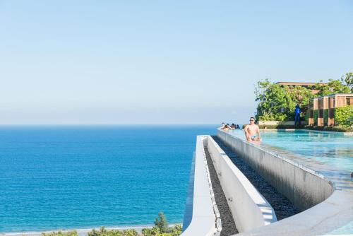 a man standing next to a swimming pool next to the ocean at Van-Pretty Residence Haitang Bay Sanya in Sanya