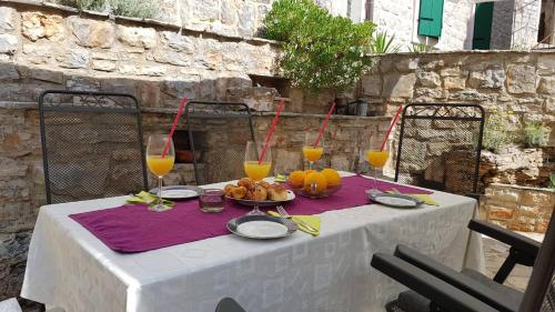 a table with a plate of fruit and glasses of orange juice at Mama's & Papa's house in Vrboska