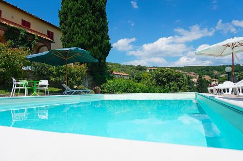 a swimming pool with an umbrella and chairs at Agriturismo Le Capanne in San Dalmazio
