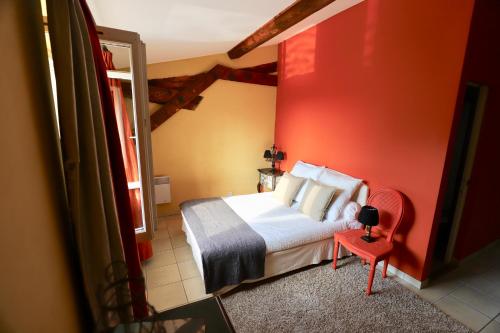 une chambre avec un lit et un mur rouge dans l'établissement Maison de Margot, à Peyriac-Minervois