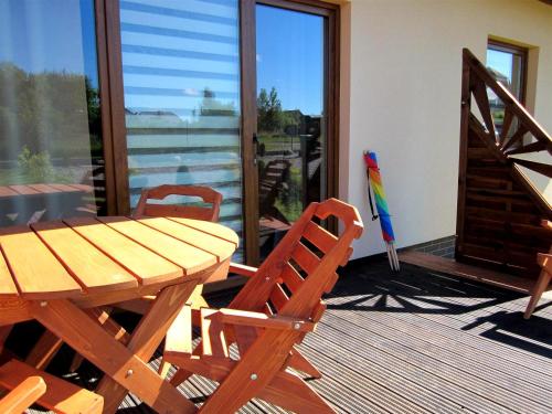 a wooden table and chairs on a deck with a table and a window at luna in Gąski