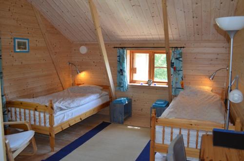 a bedroom with two beds in a wooden house at Pensionat Sågknorren in Bygget