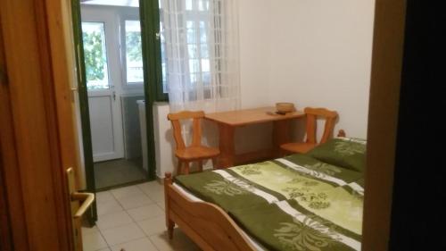 ハイドゥソボスローにあるAquaparti apartmanok Hajdúszoboszlóのベッドルーム1室(ベッド1台、テーブル、窓付)