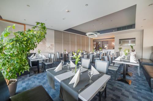 a restaurant with white tables and chairs and plants at Express Kraków Hotel in Kraków
