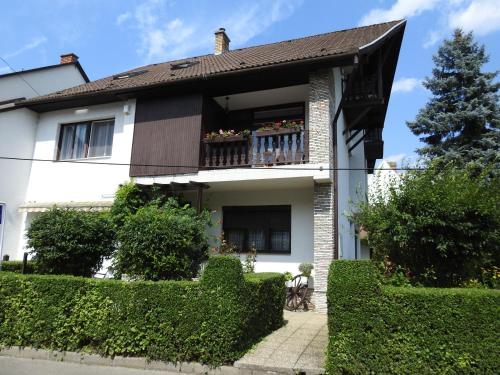 a white house with a balcony and bushes at Haus Gizella in Harkány
