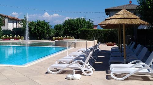 a row of chairs and an umbrella and a swimming pool at Nettuno Residence Hotel in Peschiera del Garda