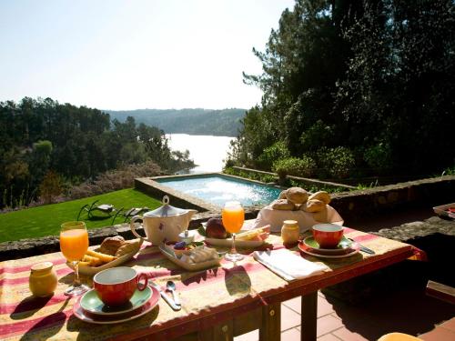 a picnic table with food and drinks and a pool at Quinta do Troviscal in Castelo do Bode