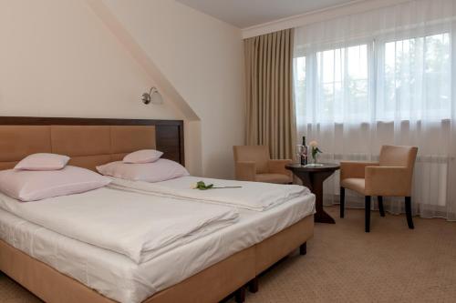 Schlafzimmer mit einem Bett mit rosa Kissen und einem Tisch in der Unterkunft Villa Diana in Rozalin