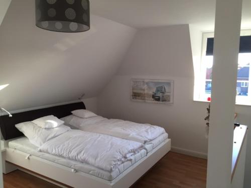ein weißes Schlafzimmer mit einem Bett mit weißer Bettwäsche in der Unterkunft Friesengut4 in Langeoog