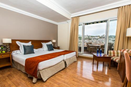 ein Hotelzimmer mit einem Bett und einem großen Fenster in der Unterkunft Leonardo Hotel Granada in Granada