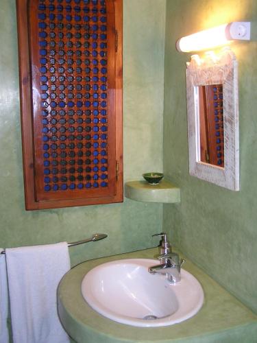 a bathroom with a sink and a mirror and towels at Dar Al Bahar in Essaouira
