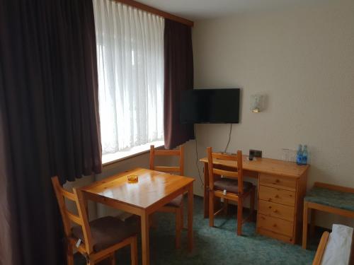 Zimmer mit einem Tisch und einem Schreibtisch sowie einem Tisch und Stühlen in der Unterkunft Hotel Grüner Baum in Bretzenheim