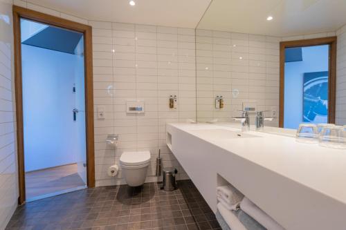 a bathroom with a toilet and a large sink at Clarion Hotel The Edge in Tromsø