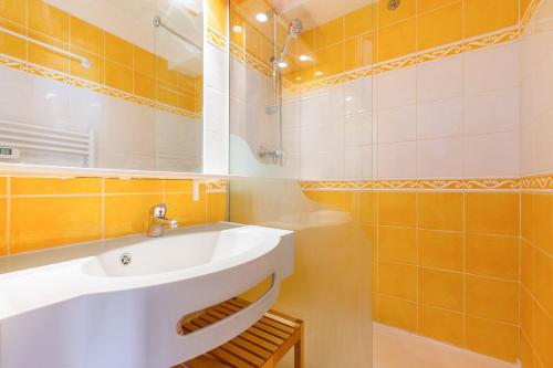 une salle de bain avec un lavabo blanc et un miroir dans l'établissement Residence Les Horizons d'Huez - maeva Home, à L'Alpe-d'Huez