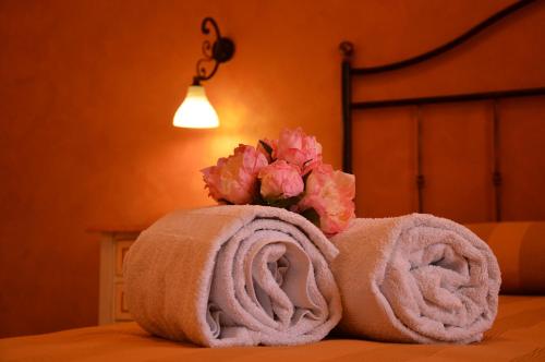 un mucchio di asciugamani su un letto con un fiore di Attinia a San Vito lo Capo