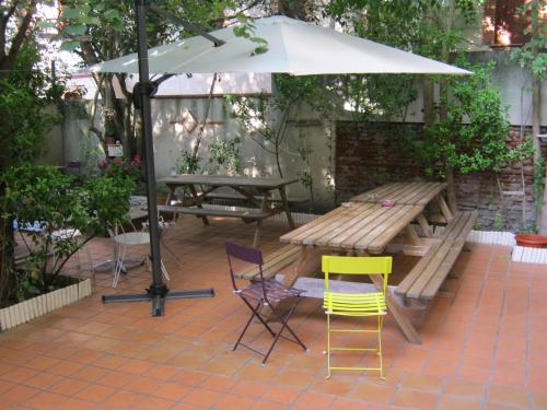 a picnic table and chairs with an umbrella on a patio at La Petite Auberge de Saint-Sernin in Toulouse