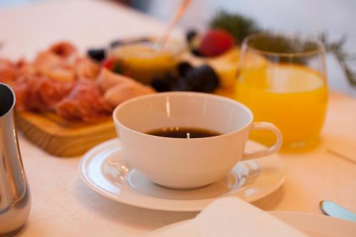 a cup of coffee on a table with a plate of food at Villa Nicolli Romantic Spa Resort - Adults Only in Riva del Garda