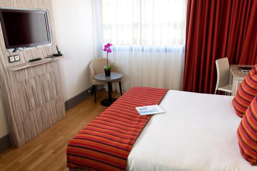 a hotel room with a bed and a tv at Eden Hotel & Spa in Cannes