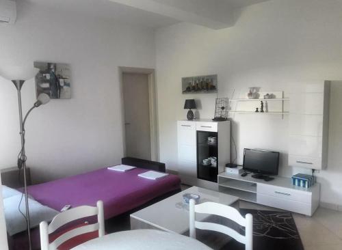 1 dormitorio con cama morada, mesa y sillas en Topla, en Herceg-Novi