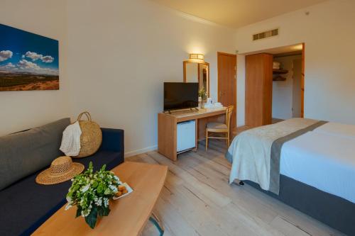 a hotel room with a bed and a couch and a table at Kinar Galilee in Kinar