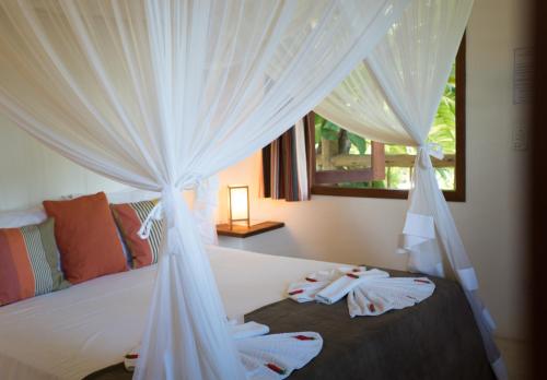 a bedroom with a bed with white curtains at Pousada Jardim Das Margaridas in Trancoso