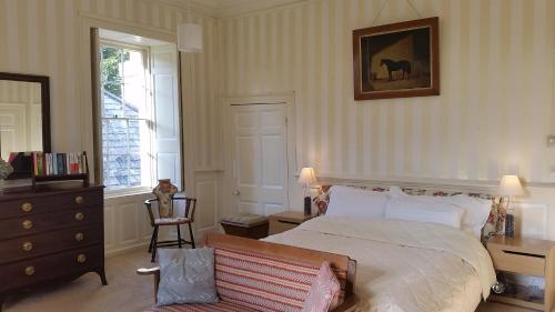 a bedroom with a bed and a chair in it at Kelly House Country B&B in Lifton