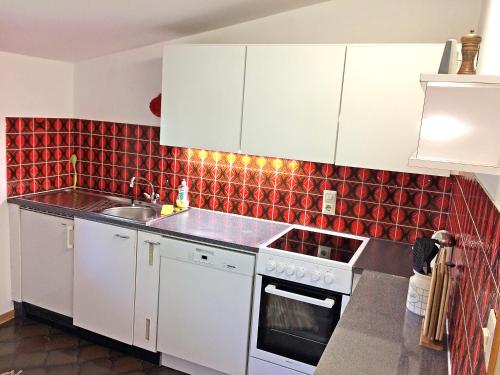 シュルンスにあるFerienwohnung Linusの白いキャビネットと赤いタイルのキッチン