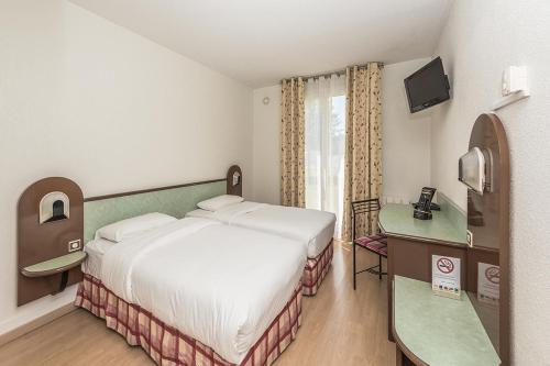 a hotel room with a bed and a television at Hostellerie Saint Vincent Beauvais Aeroport in Beauvais