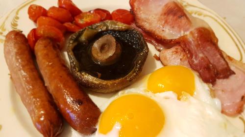 a plate of food with eggs bacon sausage and tomatoes at Kelly House Country B&B in Lifton