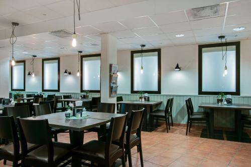 a dining room with tables and chairs and windows at First Hotel Brommaplan in Stockholm