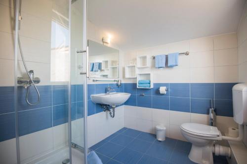 a blue and white bathroom with a toilet and a sink at Katarina apartmani in Podstrana