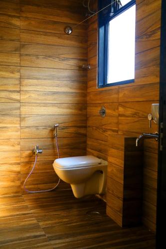 ターネーにあるHotel Alka Residencyの木製バスルーム(トイレ付)、窓が備わります。