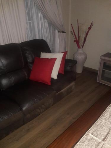 a black leather couch with two red and white pillows at Tehilah in Sabie