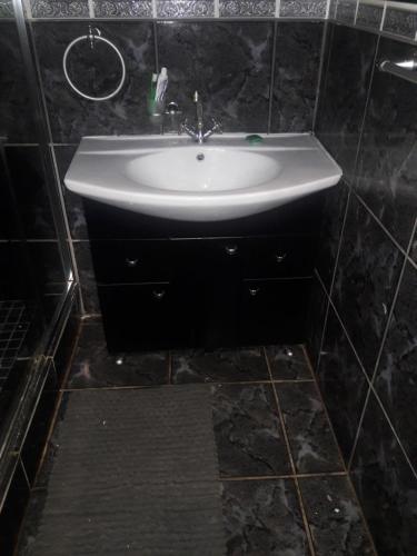 a white sink in a black tiled bathroom at Tehilah in Sabie