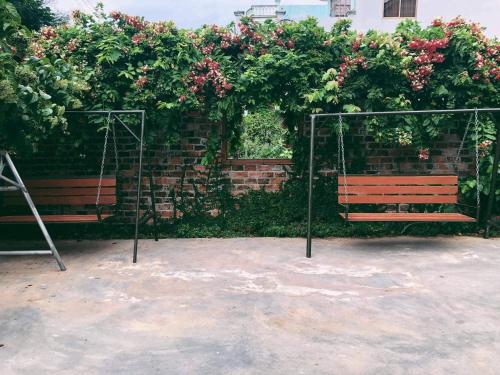 a swing in front of a brick wall with flowers at Trại Hoa Vàng Homestay at Phú Yên in Ðông Tác (1)