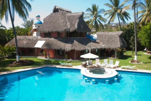 a resort with a swimming pool and a thatched building at Casa Villa Magnolia in Cruz de Huanacaxtle