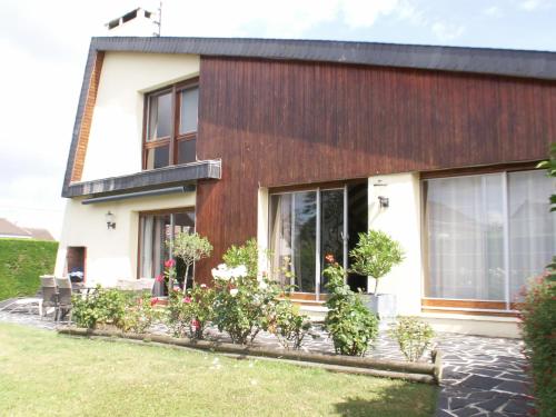 une maison avec des fenêtres et des plantes dans la cour dans l'établissement chambre normande, à Courseulles-sur-Mer