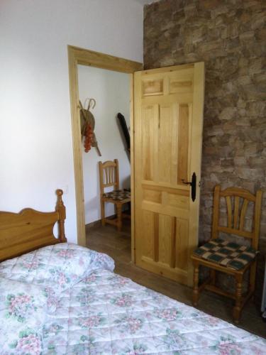a bedroom with a bed and a wooden door at Alojamiento Buena Vista in Alcalá del Júcar