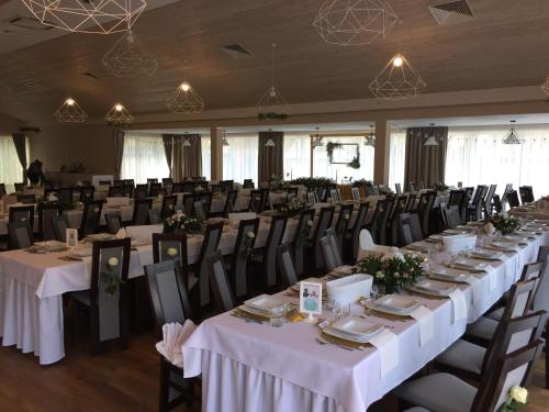 a banquet hall with tables and chairs with white tablecloths at Leśna Chata in Cieszanów