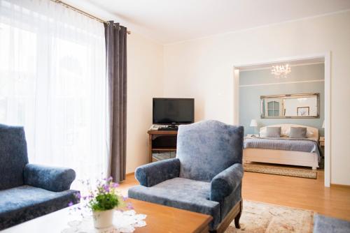 a living room with two chairs and a bed at Hotel Renusz in Gdańsk