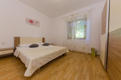 een witte slaapkamer met een bed en een raam bij Apartman Jelena 2 in Kaštela