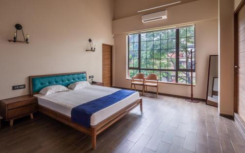 a bedroom with a bed and a large window at StayVista's Villa 39 - A stylish villa with an outdoor pool in Lonavala