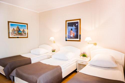 duas camas num quarto de hotel com paredes brancas em Hotel Renusz em Gdansk