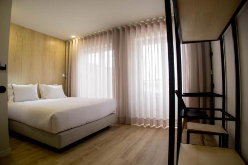 um quarto com uma cama branca e uma escada para uma janela em The Gate em Porto