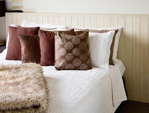 a bed with pillows on it with a white comforter at Blenheim Palms Motel in Blenheim