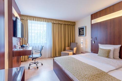 a hotel room with a bed and a desk and a chair at Best Western Macrander Hotel Frankfurt/Kaiserlei in Offenbach